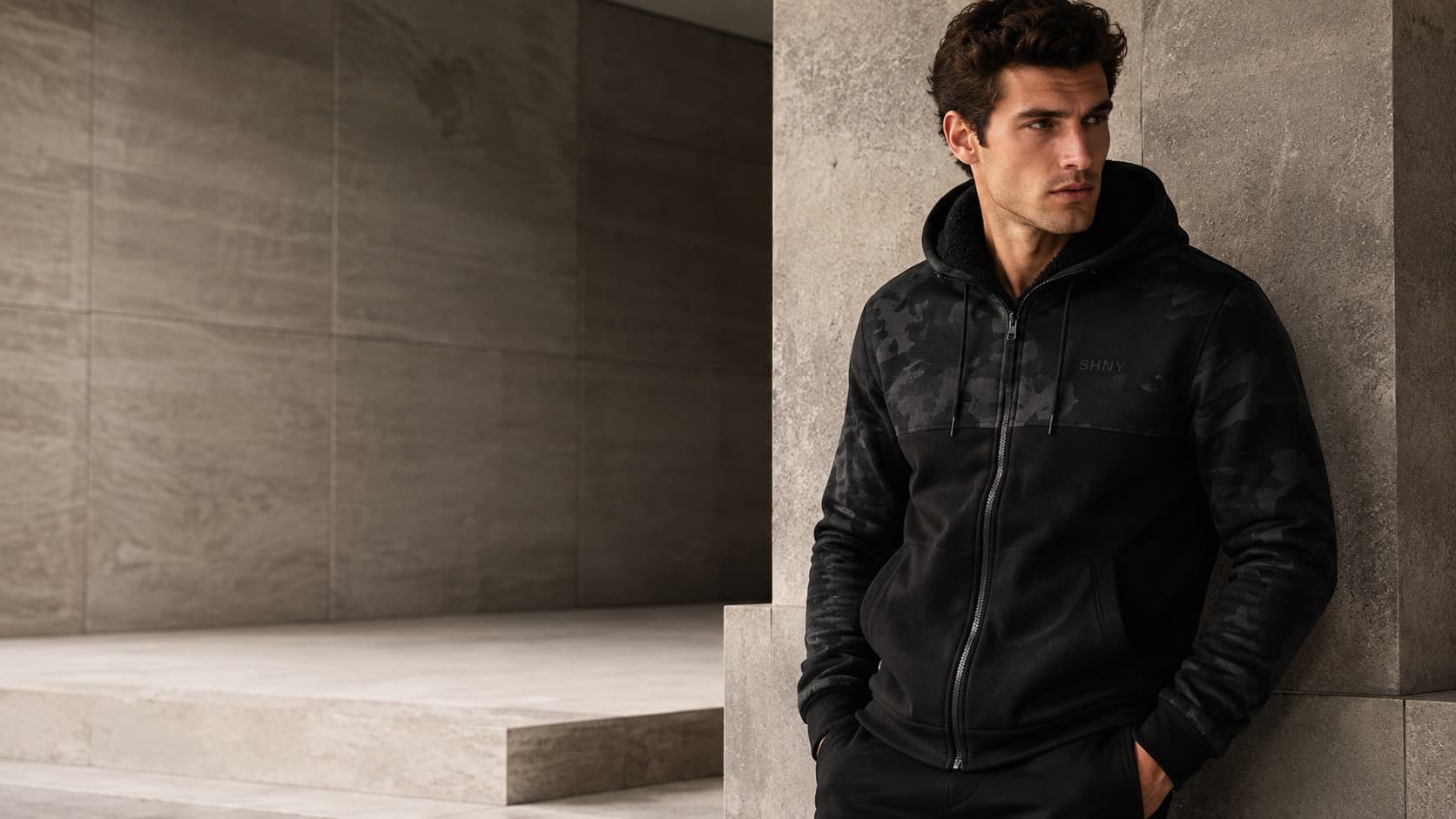SHNY Lifestyle, black camo hoodie against stone architecture